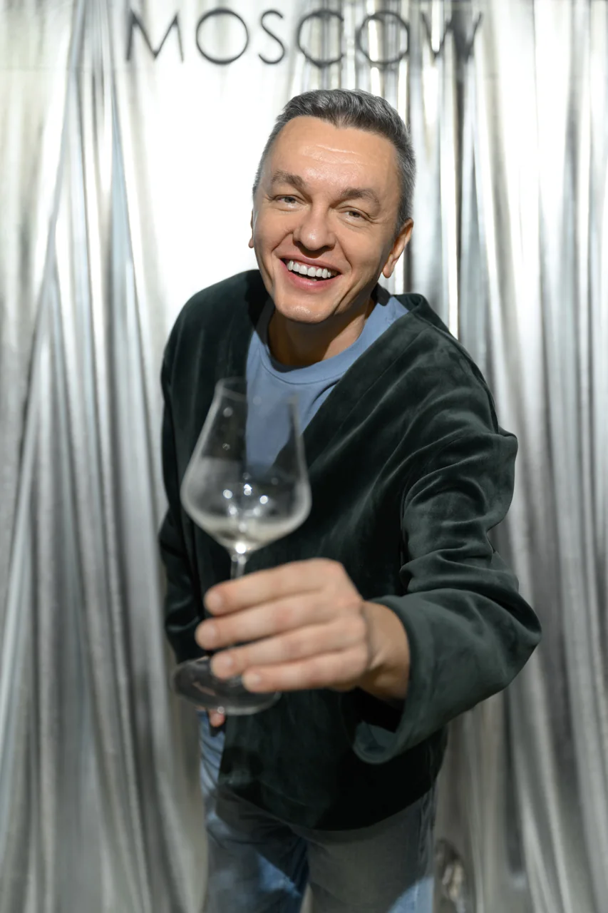 Улыбающийся гость с бокалом у фотозоны WineWood